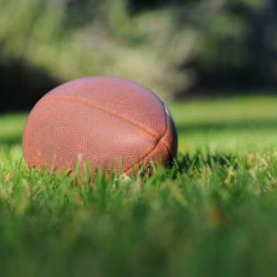 Photograph of a football resting on grass, clickable link to Edgewater High School's Incoming Athletes information page.